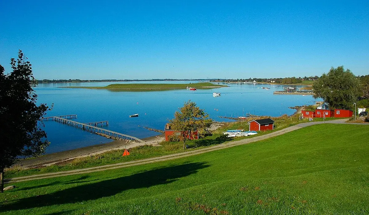 Scenic view of Roskilde Fjord with calm water, boats, and grassy shoreline near Jyllinge.