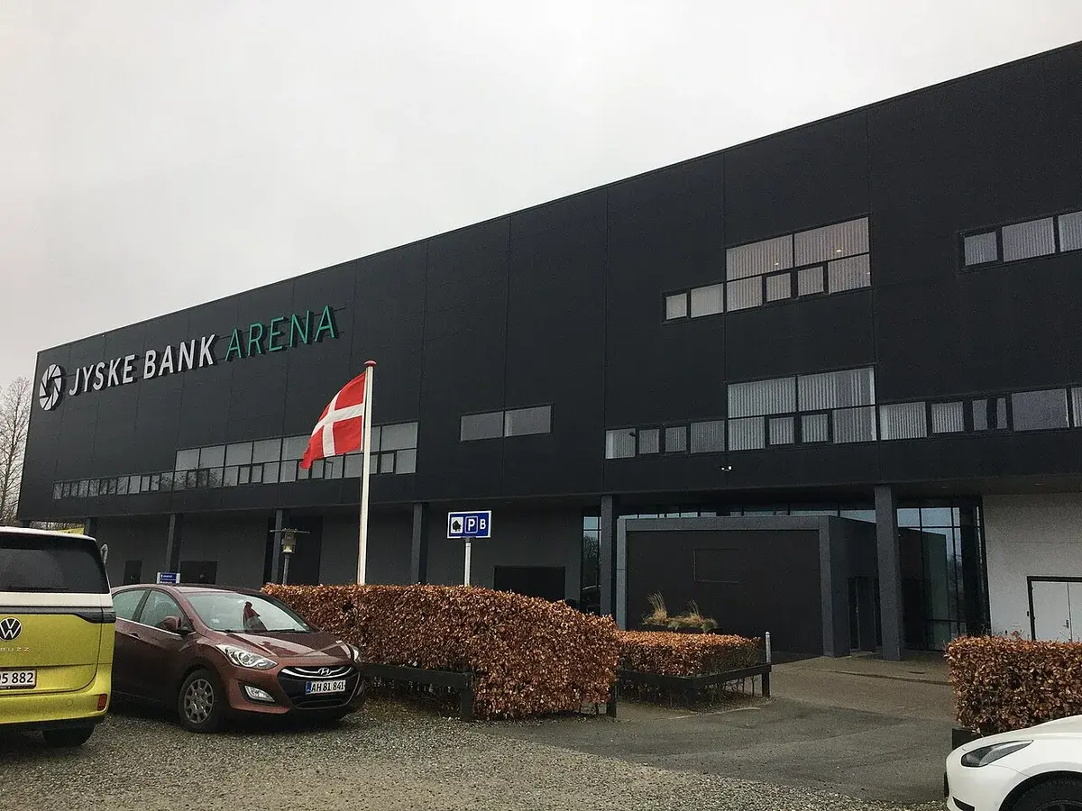 Exterior of Jyske Bank Arena in Odense with a Danish flag in front.