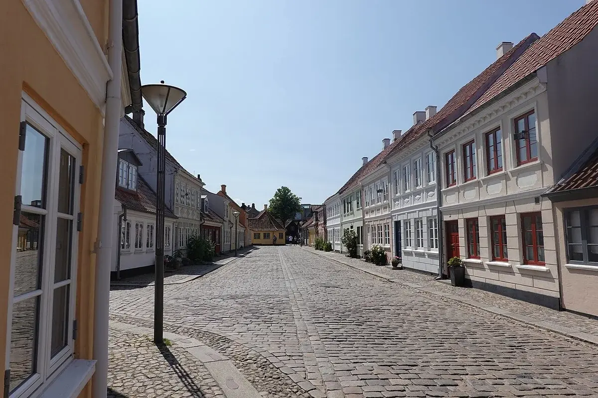 A quiet cobblestone street lined with historic houses in Odense, Denmark.