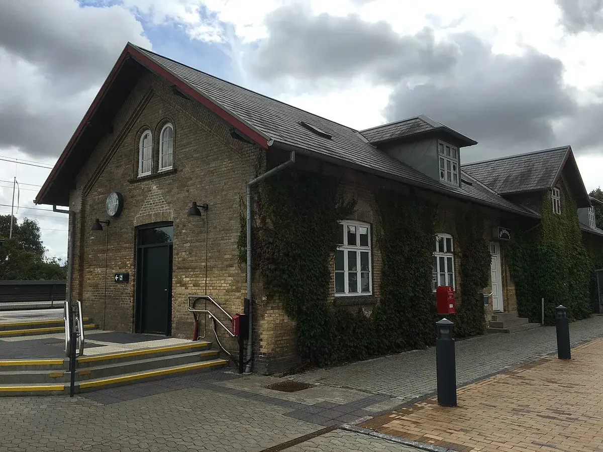 Train station building seen from a parking lot under cloudy skies.
