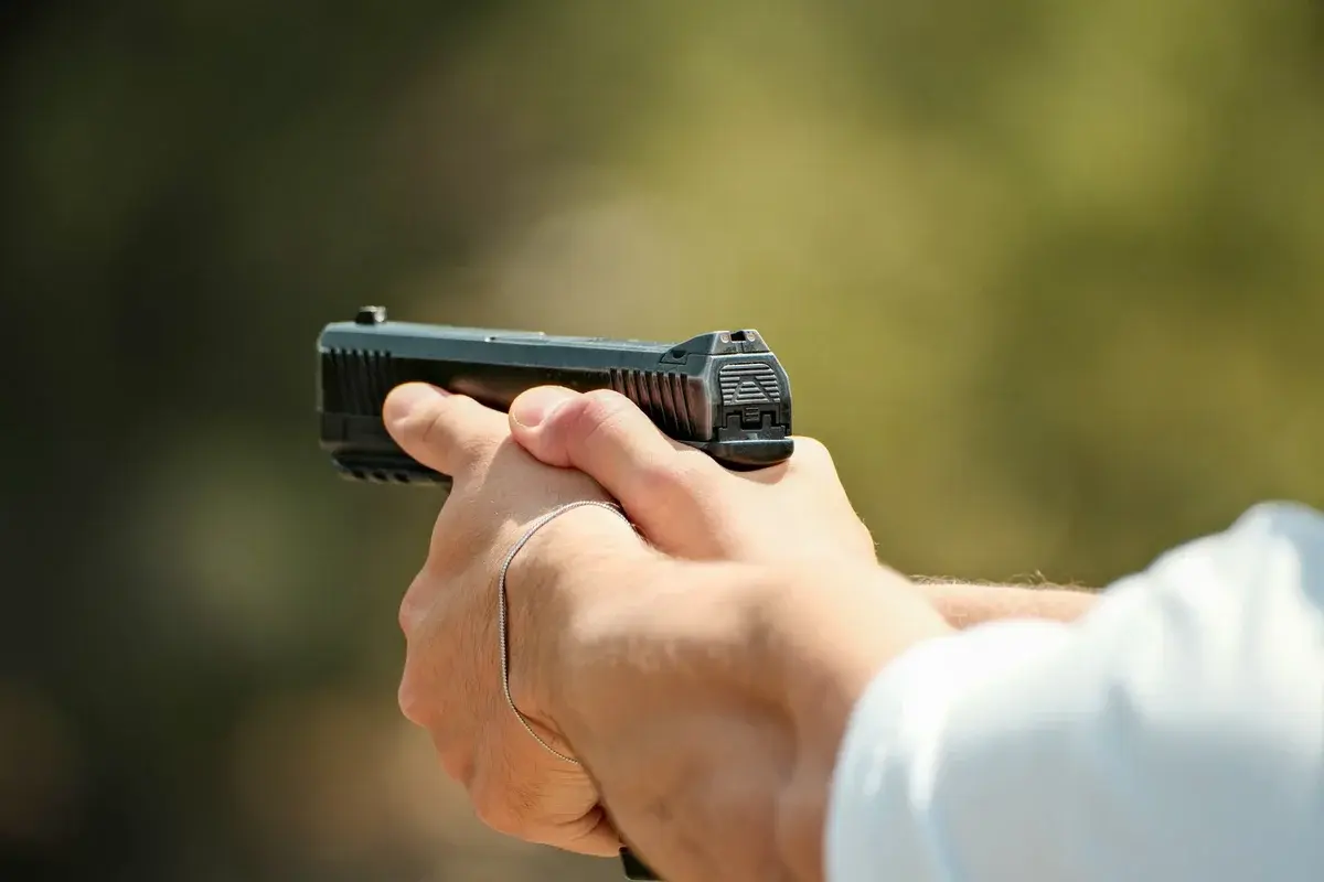 Close-up of hands holding a pistol outdoors.