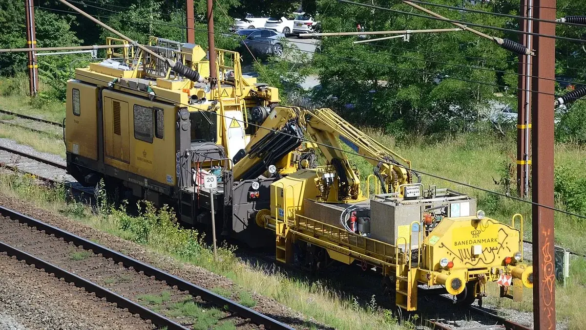 A yellow Banedanmark railway service vehicle on a track in Kolding, Denmark.