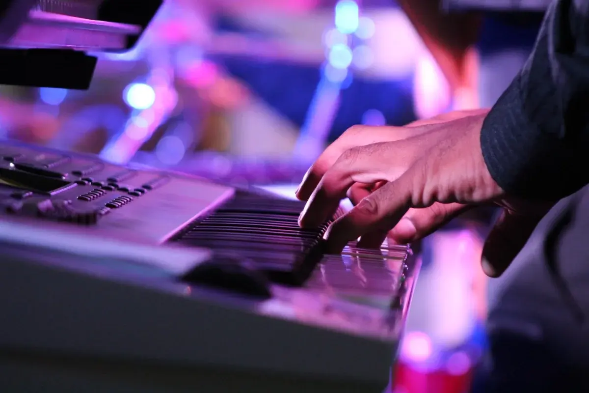 Hands playing an electric keyboard on stage.