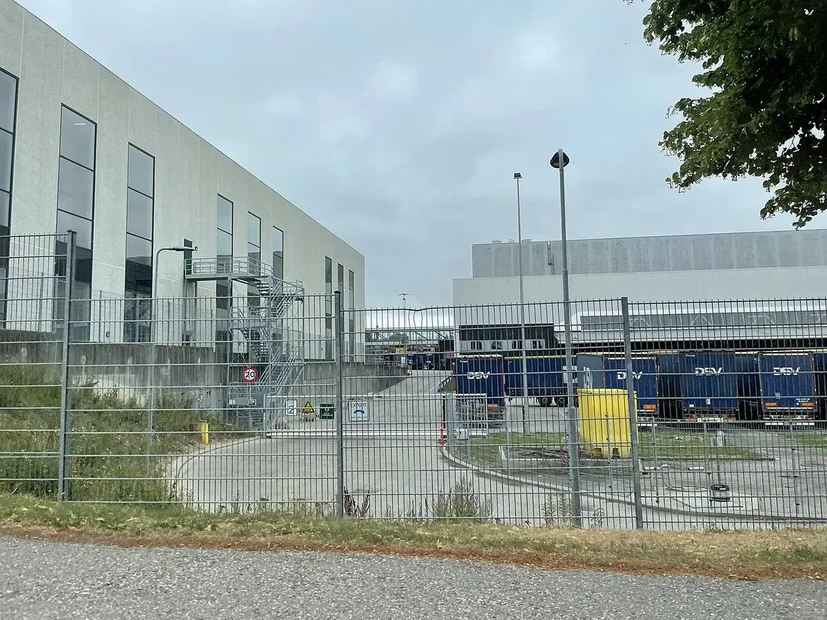 Fenced brewery industrial complex with factory buildings and trailers.